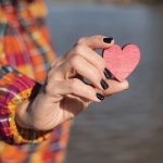 Person holding red wooden heart in hand