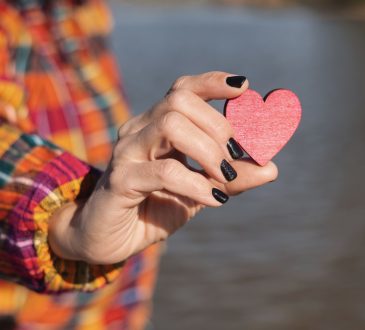 Person holding red wooden heart in hand