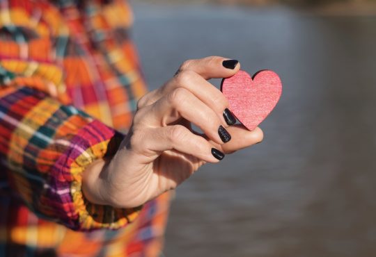 Person holding red wooden heart in hand