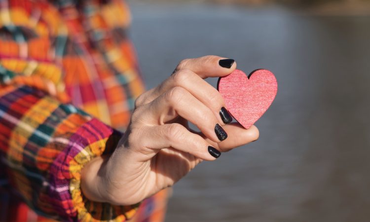 Person holding red wooden heart in hand