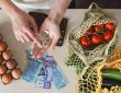 Groceries on counter surrounding hands of person counting cash