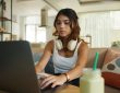 Serious teenage girl with headphones working on laptop