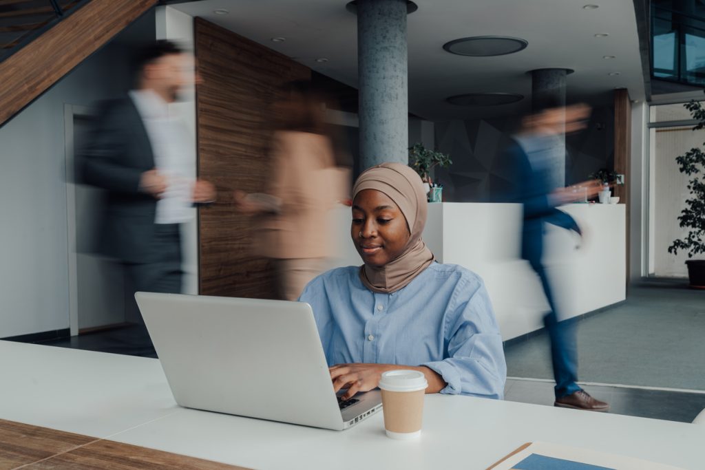 Young muslim businesswoman concentrating on her work on a laptop in a dynamic office environment