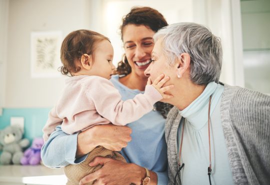 Grandmother, mother and baby in home playing