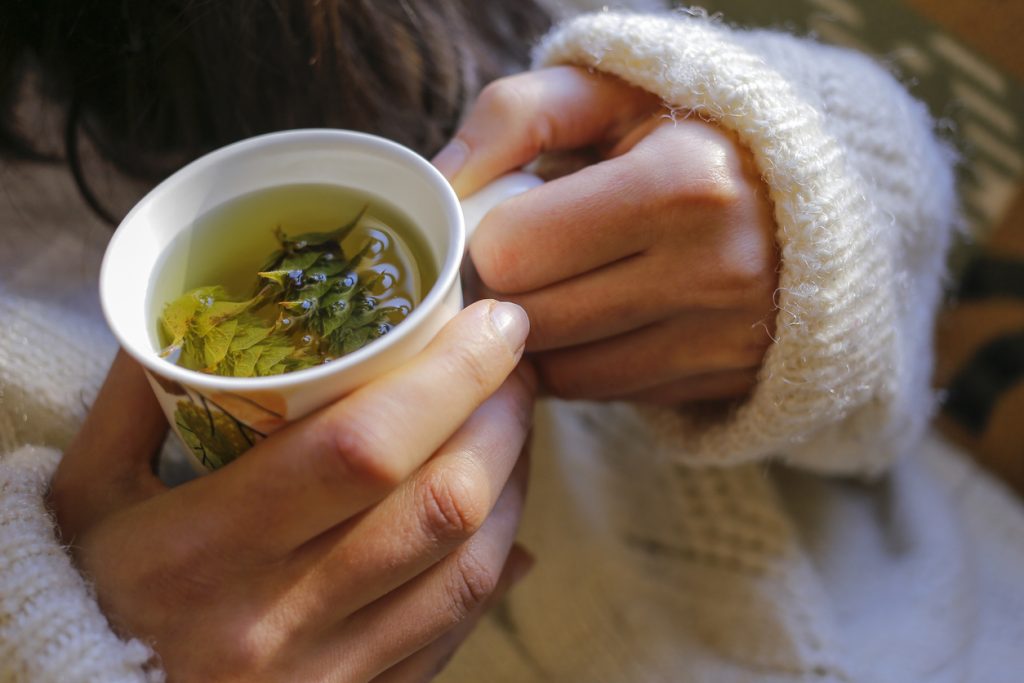 Close up of hands holding mug of tea