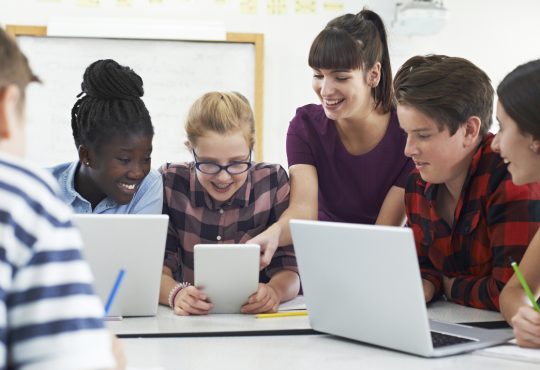 Teenage Students With Teacher In IT Class