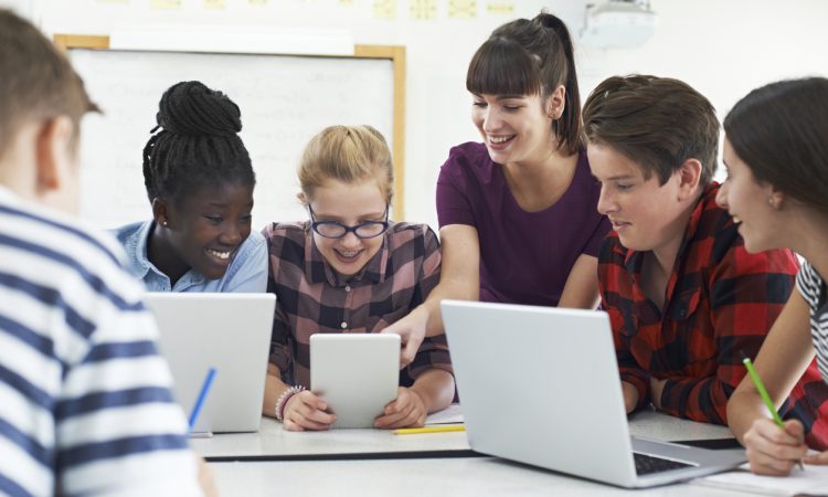 Teenage Students With Teacher In IT Class