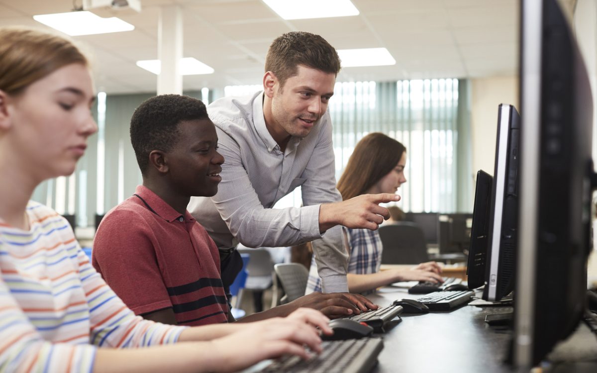 Teacher helping students in computer lab