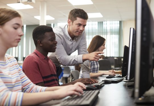 Teacher helping students in computer lab