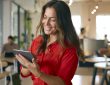 Woman smiling and looking at tablet in office