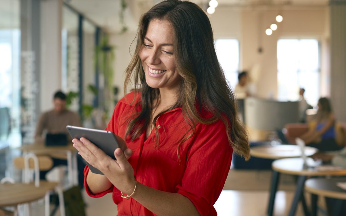 Woman smiling and looking at tablet in office
