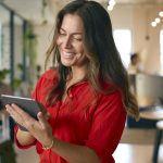 Woman smiling and looking at tablet in office