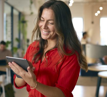 Woman smiling and looking at tablet in office