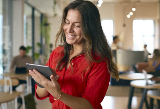 Woman smiling and looking at tablet in office