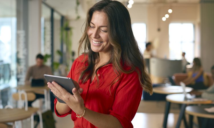 Woman smiling and looking at tablet in office