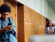 Teen texting in hallway of school
