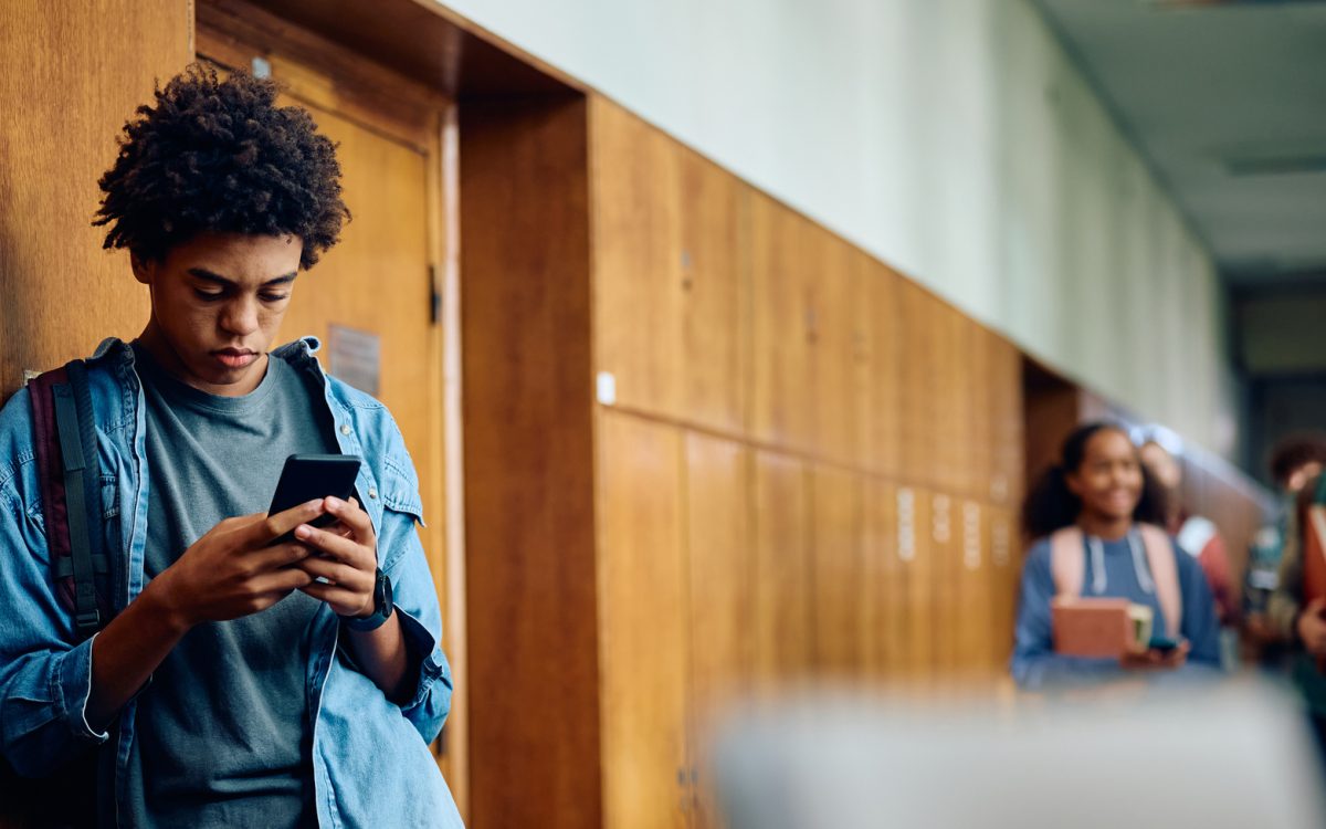 Teen texting in hallway of school