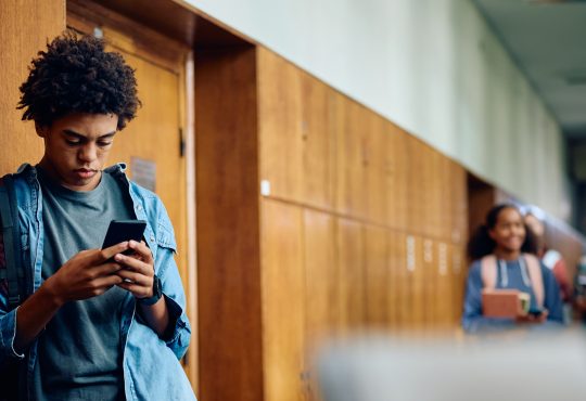 Teen texting in hallway of school