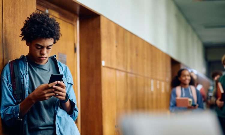 Teen texting in hallway of school