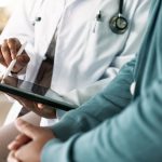 Closeup of hands of doctor looking at tablet