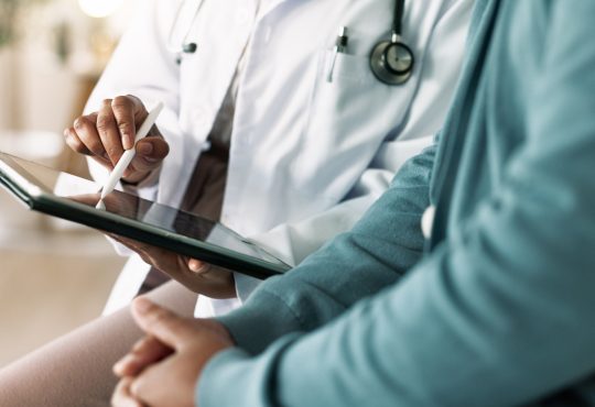 Closeup of hands of doctor looking at tablet