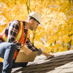 Man inspecting roof of house