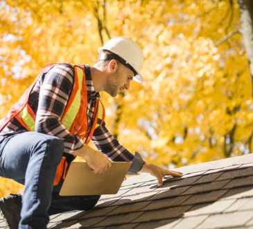 Man inspecting roof of house