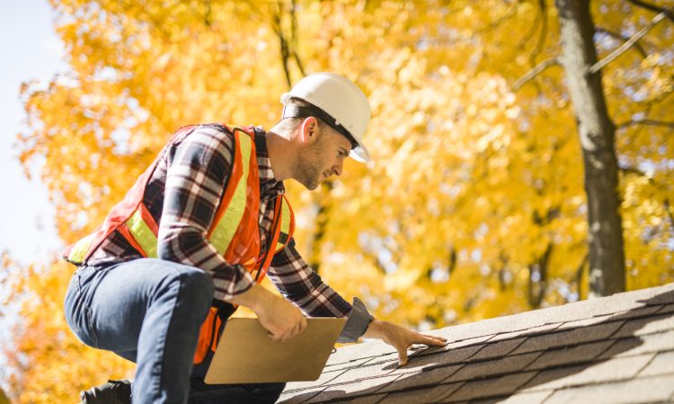 Man inspecting roof of house
