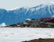 n Photo of Pond Inlet in mid June of 2005 from Salmon Creek, 3.5 kms West of the Hamlet. The mountains are 25kms away and the iceberg is 9kms from town. The community's library (large white roof) and Health Center (large red roof) are the most predominent structures in the photo.