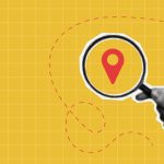 Photo illustration of hand holding magnifying glass on top of map