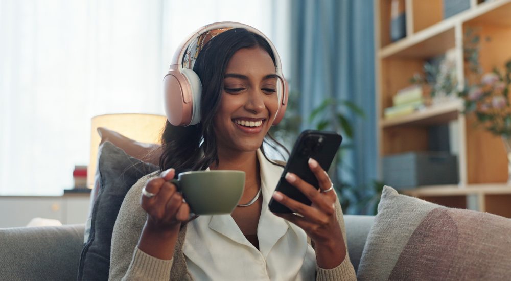 Woman listening on headphones while drinking tea