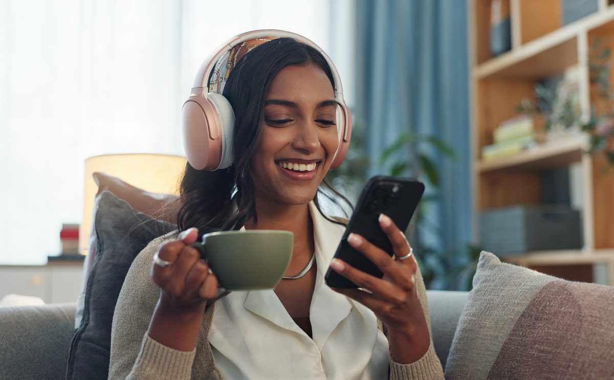 Woman listening on headphones while drinking tea