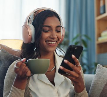 Woman listening on headphones while drinking tea