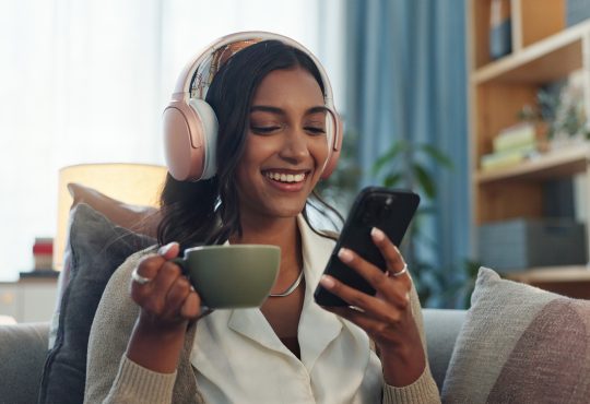 Woman listening on headphones while drinking tea