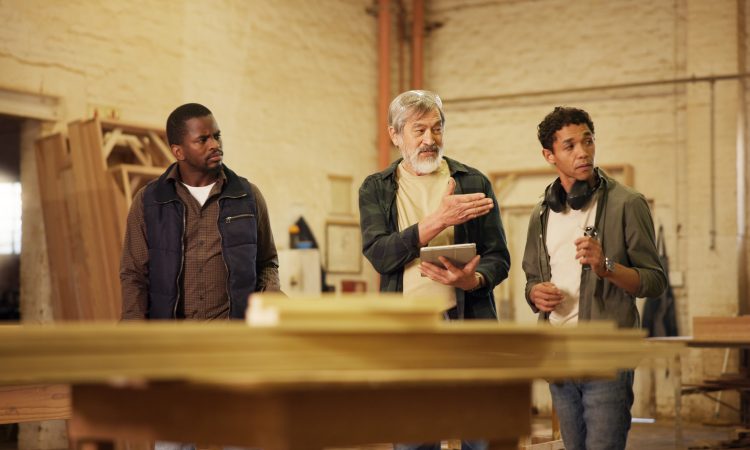 Workshop, men and group with tablet, carpenter or discussion with research, woodworking or technique. People, mature mentor and review of info