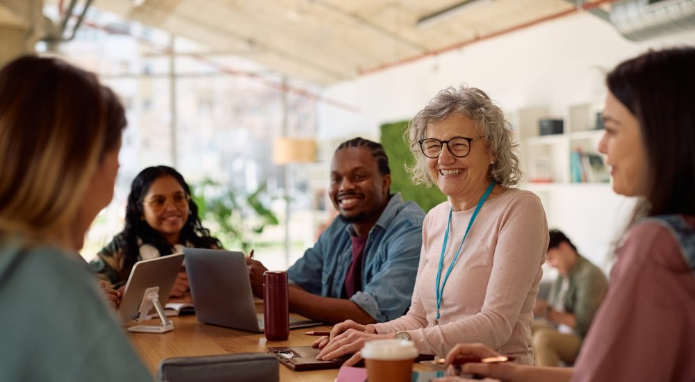 Happy mature professor and her students talking at university classroom.