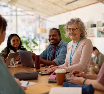 Happy mature professor and her students talking at university classroom.
