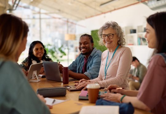 Happy mature professor and her students talking at university classroom.