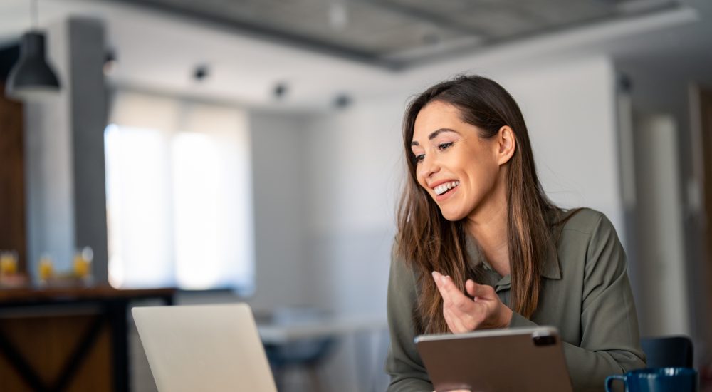 Happy confident woman video calling on laptop