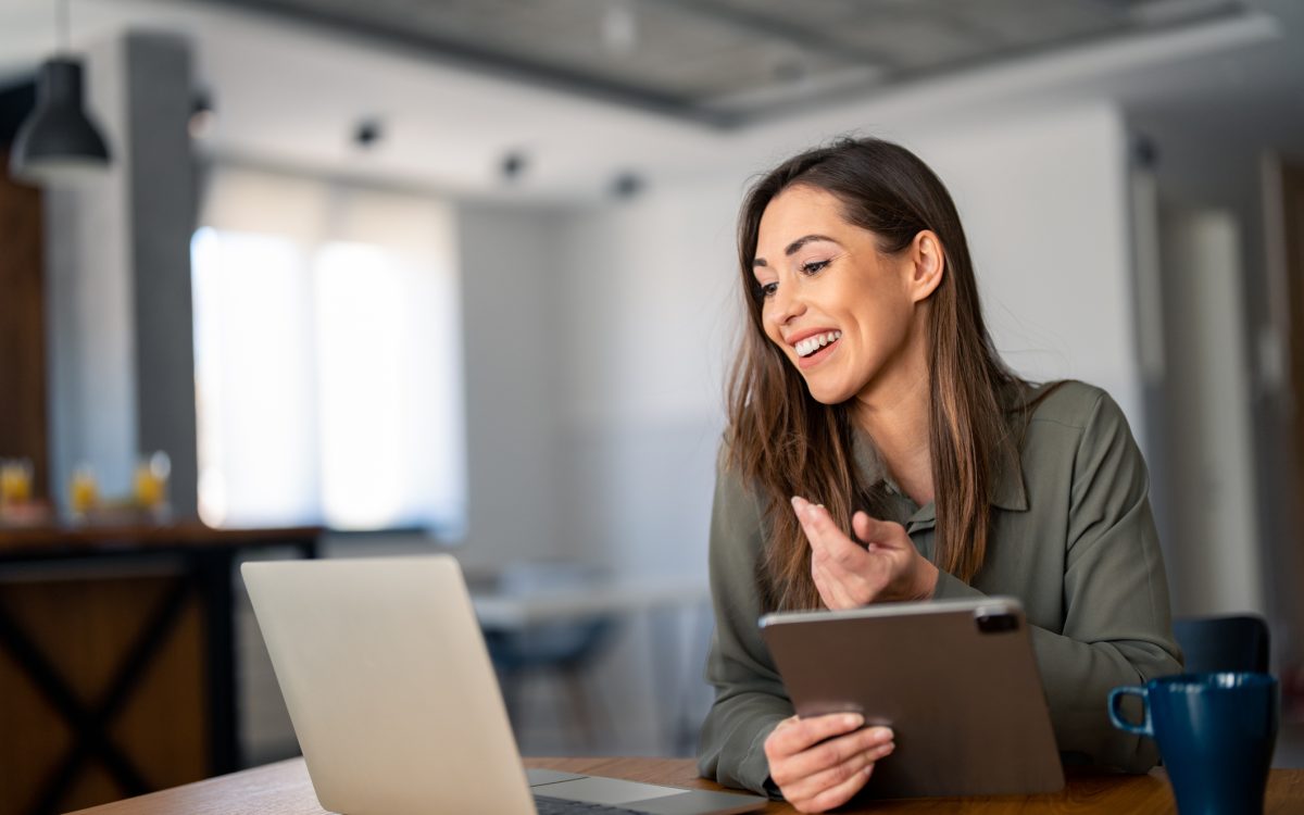 Happy confident woman video calling on laptop