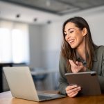 Happy confident woman video calling on laptop