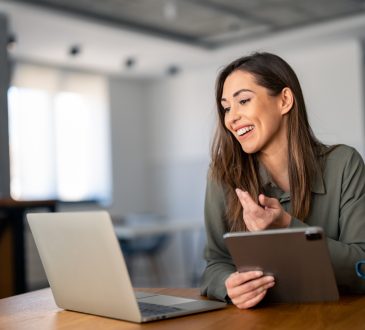 Happy confident woman video calling on laptop