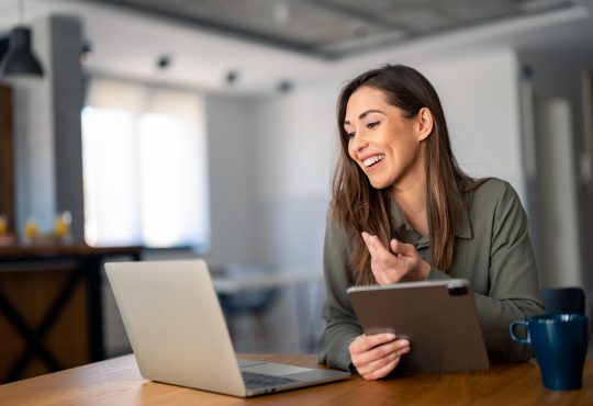 Happy confident woman video calling on laptop