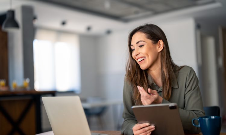 Happy confident woman video calling on laptop