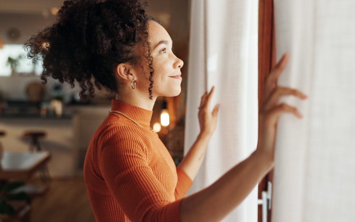 Curtains, happy woman and thinking of future in home, planning and reflection of mindset with view. Window, smile and African girl with vision, ideas and dream for morning inspiration in living room