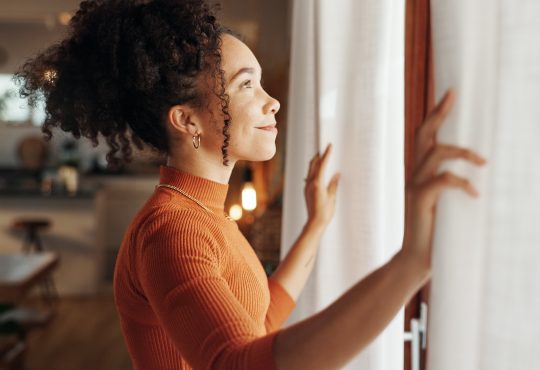Curtains, happy woman and thinking of future in home, planning and reflection of mindset with view. Window, smile and African girl with vision, ideas and dream for morning inspiration in living room