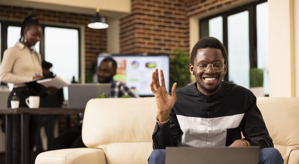 Black man waving towards laptop screen