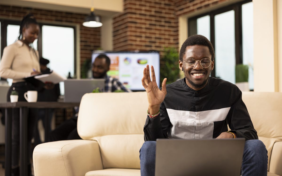 Black man waving towards laptop screen