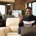 Black man waving towards laptop screen