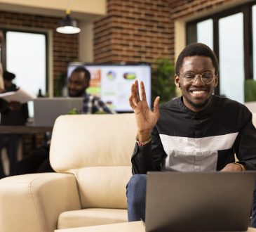 Black man waving towards laptop screen